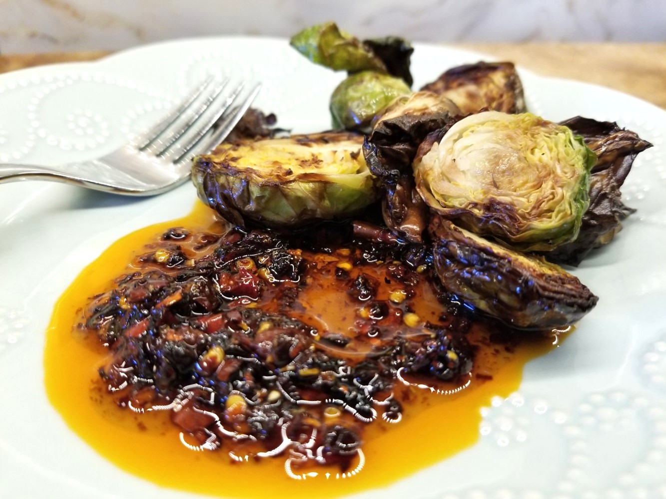 a puddle of Maple Chili Crisp with air-fried Brussels sprouts