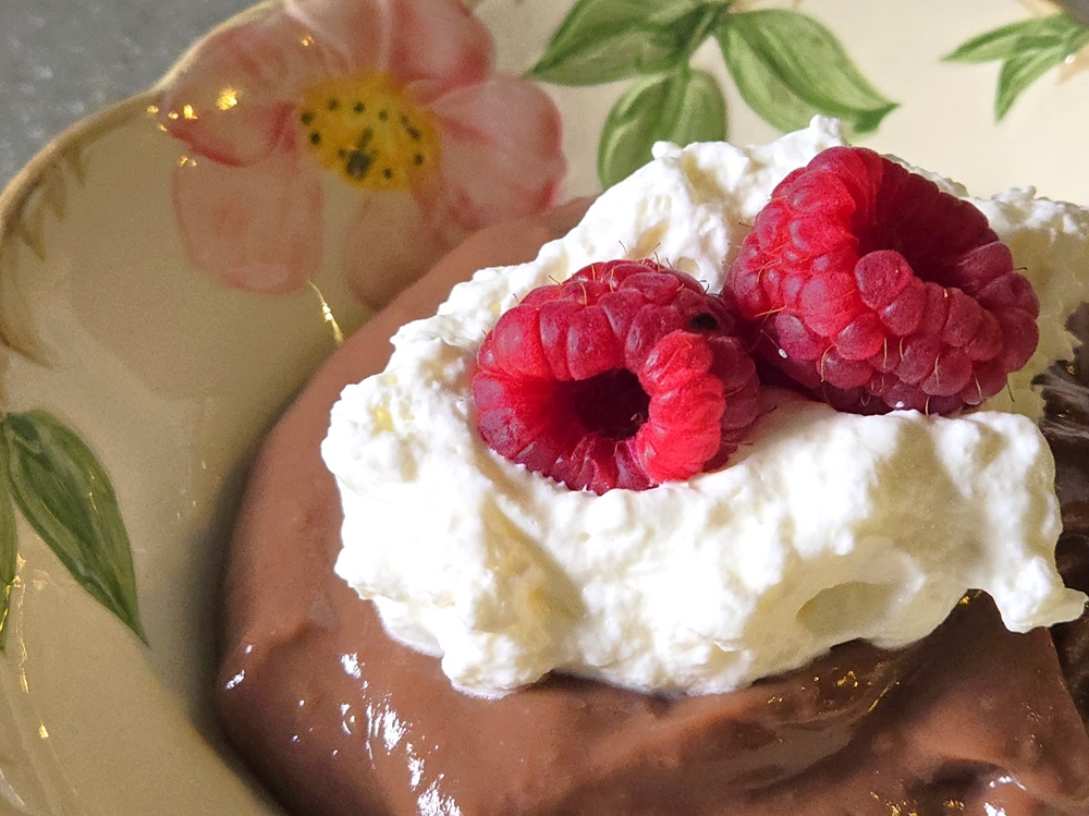 Warm Chocolate Pudding with whipped cream and raspberries